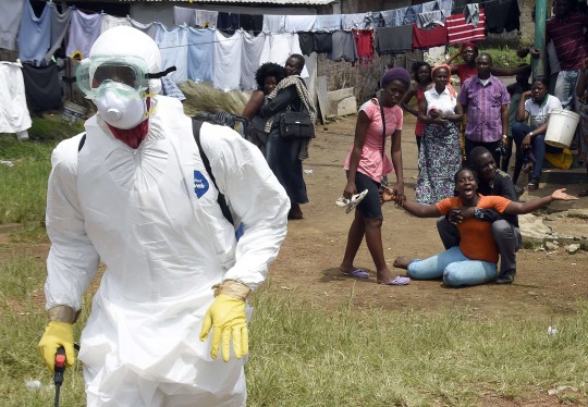 TOPSHOTS - FOTOS AFP DEL AÑO 2014 - La gente ve a una mujer reaccionar después de que se sospecha que su esposo murió por el virus del Ébola en la capital de Liberia, Monrovia, el 4 de octubre de 2014.  Con mucho, la epidemia de ébola más mortífera registrada se ha extendido a cinco países de África occidental desde principios de año, infectando a más de 7.000 personas y matando a aproximadamente la mitad de ellas.  AFP FOTO / PASCAL GUYOT.PASCAL GUYOT / AFP / Getty Images