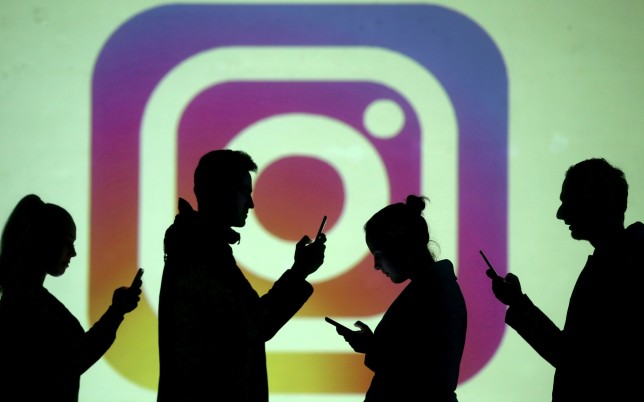 Las siluetas de los usuarios móviles se pueden ver junto con una proyección de pantalla del logotipo de Instagram.